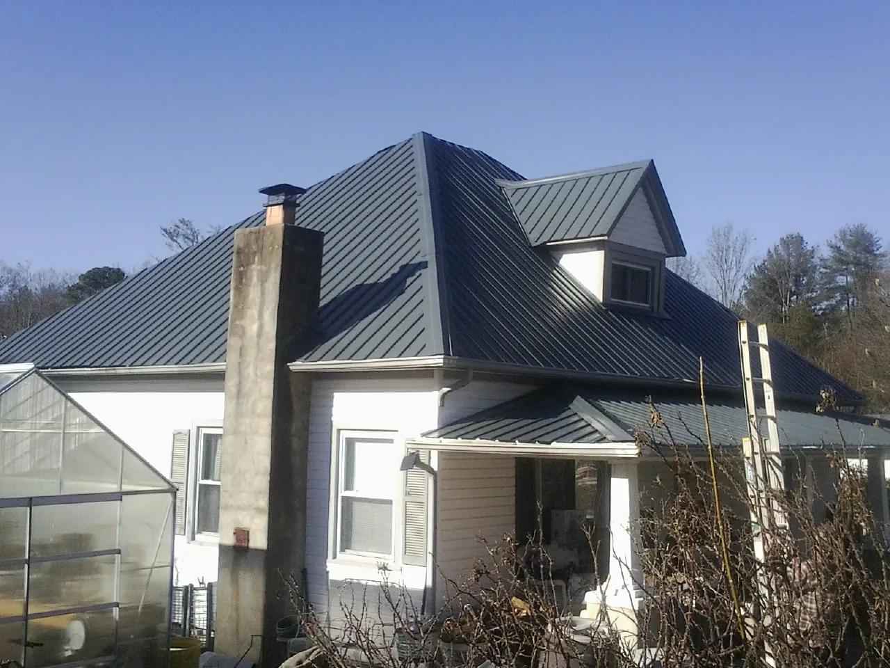 Dark blue standing seam metal roof on a white farmhouse with dormer — Slate & Tile Roof Repair by Roofing Brothers in Wexford