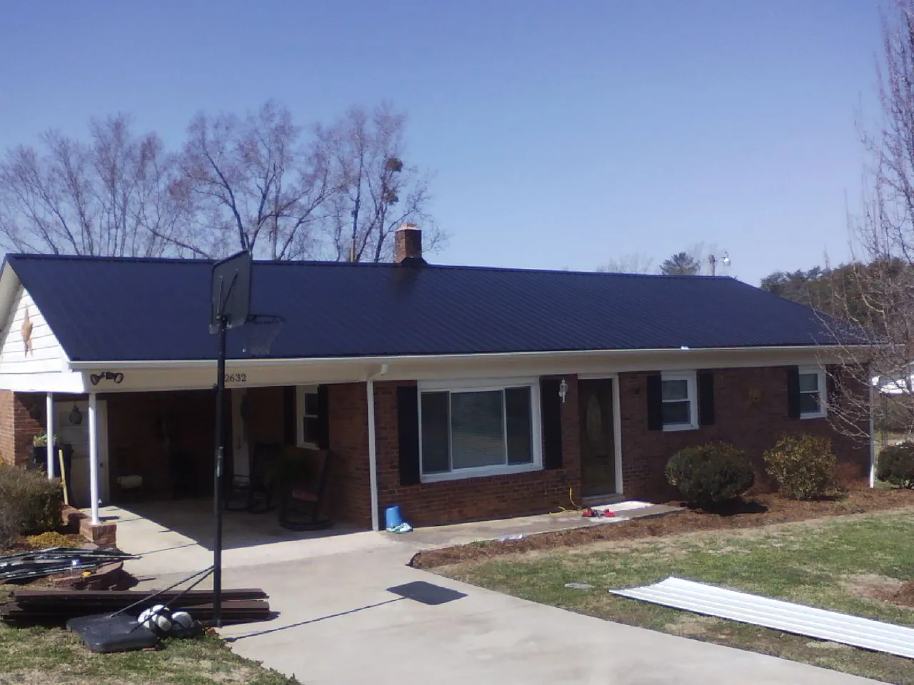 Finished dark blue metal roof on a brick ranch with a carport in Wexford
