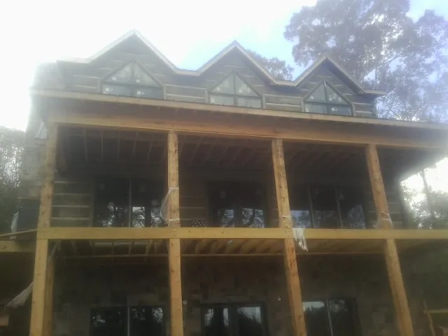 Dormers and porch framing on a large log home under construction — Roof Coating work by our crew in Wexford