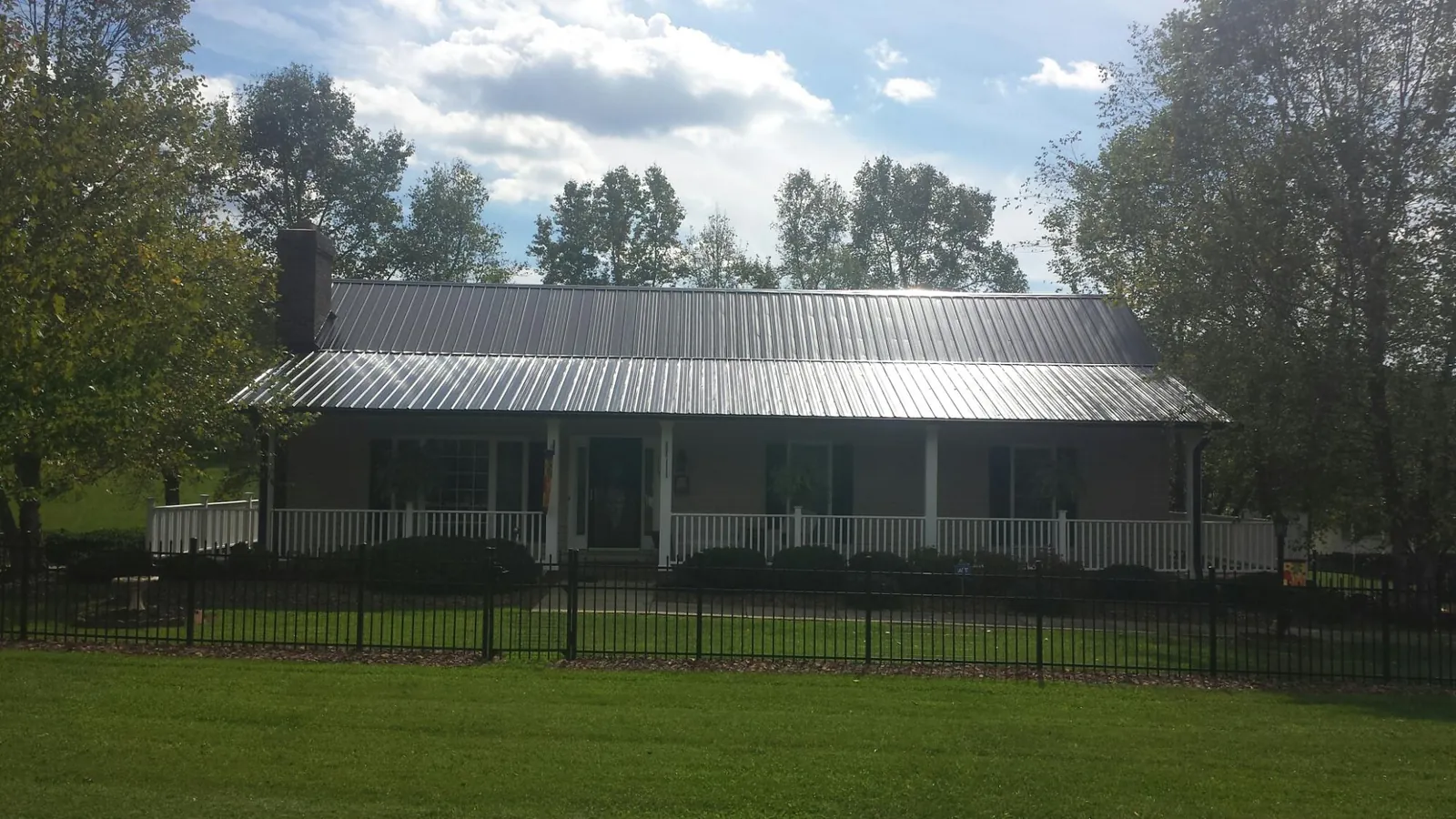 Gray metal roof on a brick ranch with a full width front porch — Gutter Guard Installation work by our crew in Wexford