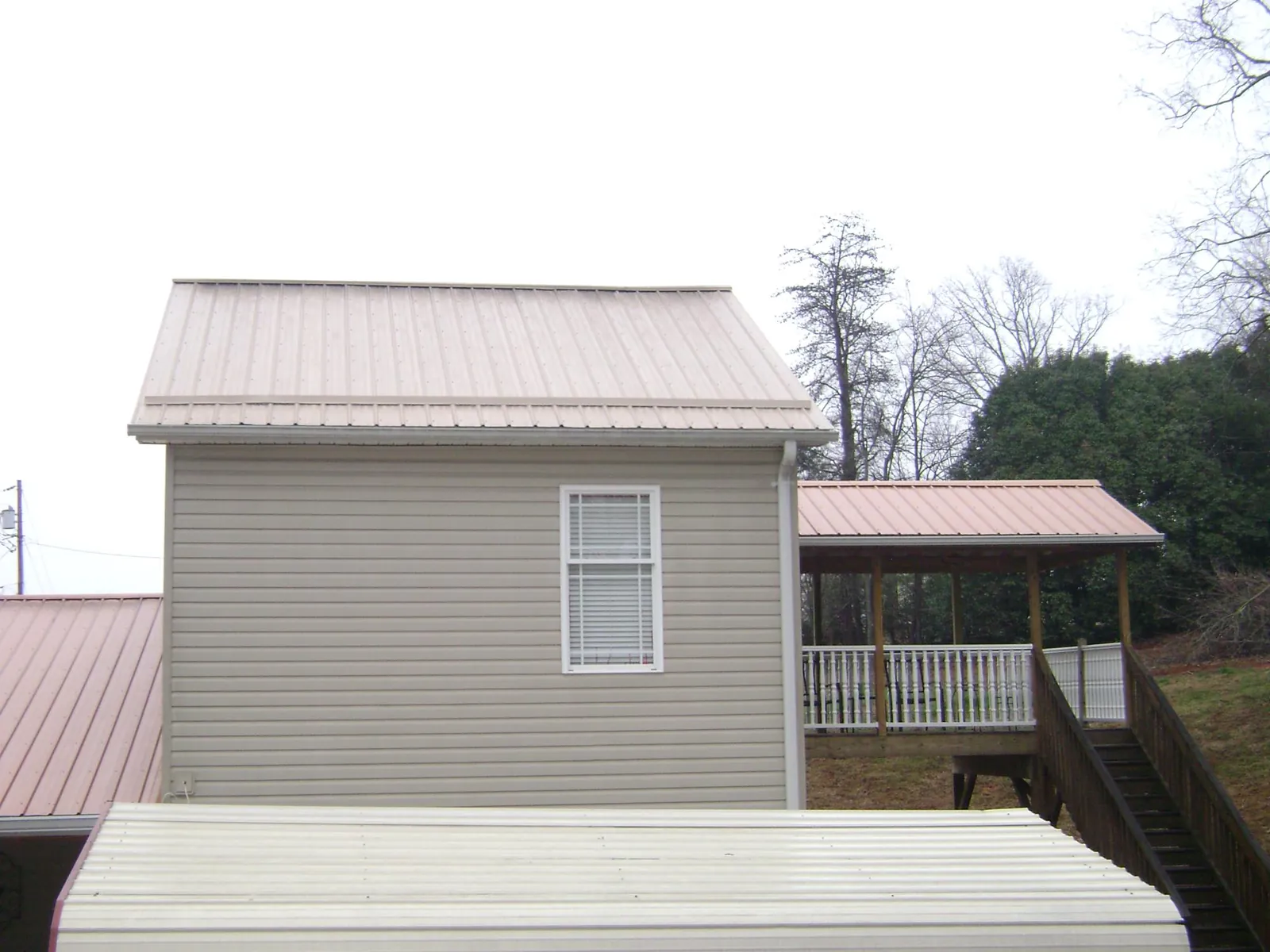 Tan metal roofs on a two story addition and attached porch, from a Roof Replacement job in Wexford