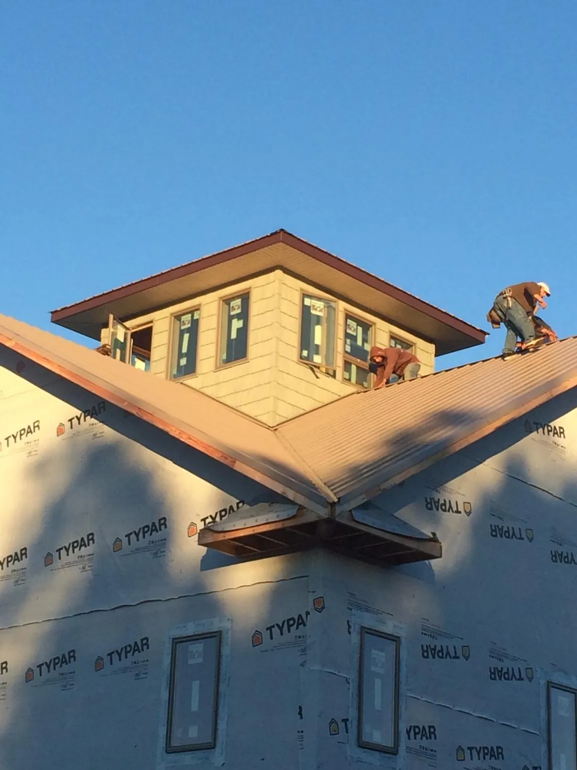 Roofers working around a rooftop cupola on a new metal roof at sunset — Roof Waterproofing in Wexford by Roofing Brothers